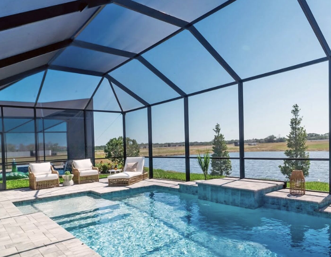 A screened lanai and pool with a lake view at Gracewater at Sarasota